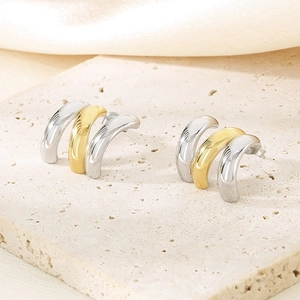 Vue macro de boucles d'oreilles créoles multicouches en or et argent sur pierre