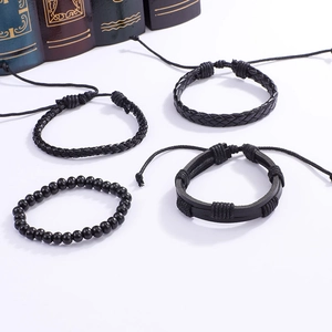Détail de quatre bracelets en cuir noir tressé avec perles de bois sur livres anciens