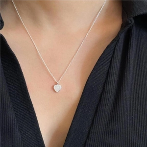 Delicate 925 sterling silver heart necklace with white stone on skin close-up