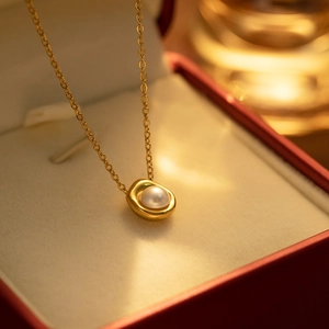 Detailed macro view of a gold pearl pendant necklace resting in a red jewelry gift box