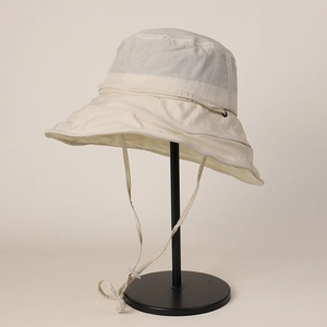 Detailed close-up view of a beige quick-dry wide-brim sun hat on a black display stand