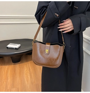 Close-up of vintage brown leather bucket bag with glossy texture and gold metal buckle
