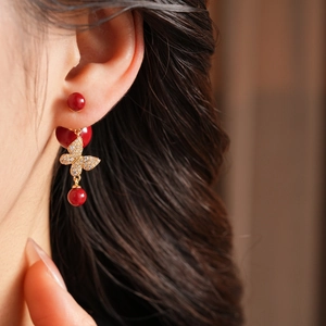 Detail of vintage butterfly earring with zircon inlay and red pearl on model