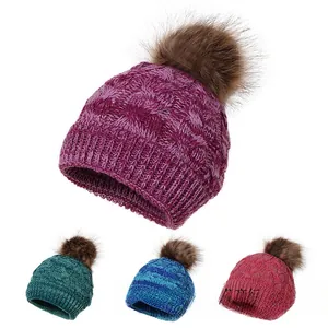 Detail of cable knit wool hats with faux fur pompom in four vibrant colors