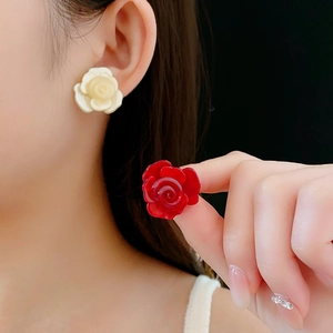 Détail de boucles d'oreilles roses en résine crème et rouge portées par un mannequin
