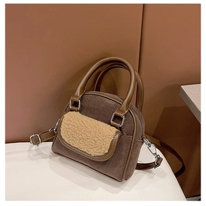 Detail of plush beige faux fur trim on a brown faux suede handbag with leather handle