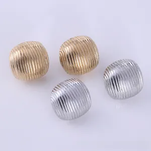 Detail of metallic liquid lava stud earrings with vertical striped texture in gold and silver