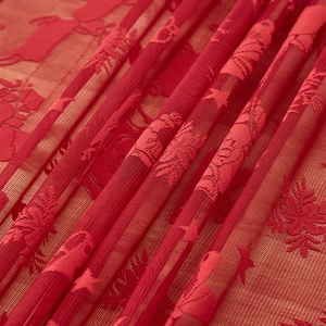 Détail de nappe de Noël en dentelle rouge avec motifs de rennes et flocons brodés