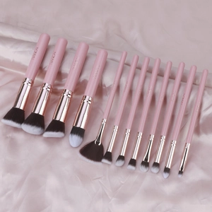 Close-up of 13-piece pink makeup brush set with gradient bristles on silk background