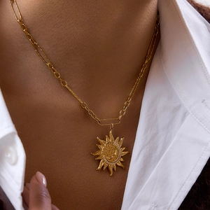 Detail of gold sun and moon pendant necklace worn by model showing vintage texture