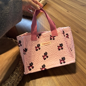 Primo piano della borsa tote rosa in seersucker con motivi di gatti neri e manici in tela