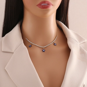 Close-up of golden necklace with crystal chain and blue evil eye star charms on mannequin