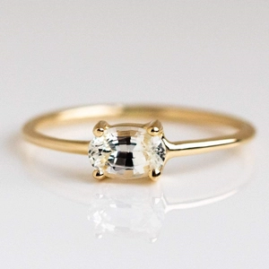 Detailed view of an oval white gemstone set in a sleek gold-plated brass ring