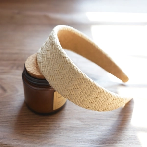 Macro detail of hand-woven beige raffia straw texture on a wide padded headband