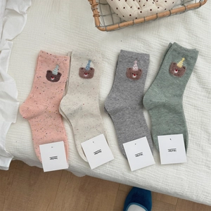 Close-up of cotton socks with embroidered bear in party hat and branded tags