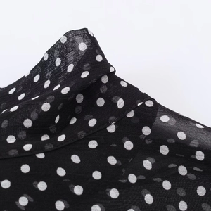 Vista macro dettagliata del tessuto in chiffon nero a pois bianchi con cuciture