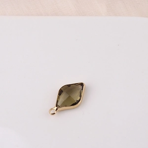 Detailed view of olive green marquise crystal pendant set in a golden metal frame
