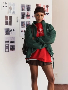 Fashionable forest green zip hoodie and red printed tee styled with a pleated skirt