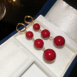 Detail of red resin beads and gold plated tassel earrings in a blue velvet gift box