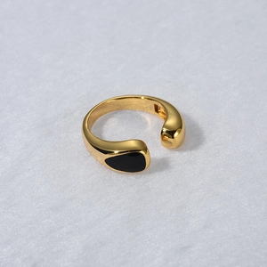Detail of minimalist gold-plated adjustable ring with black teardrop inlay for women