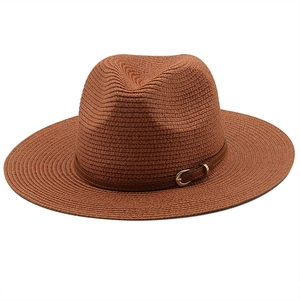 Close-up of straw fedora hat featuring a brown leather band and golden buckle detail