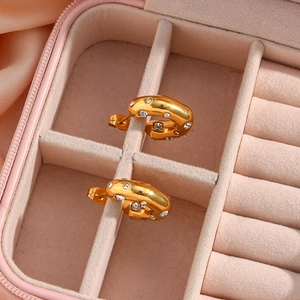 Detailed macro view of 18K gold C-shaped earrings with zircons in a pink velvet box