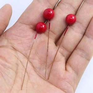 Detail of three artificial red berry stems held in hand for Christmas DIY crafts