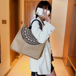 Close-up of ethnic linen tote bag with black geometric patterns and woven handles
