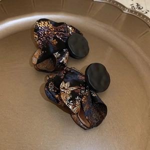 Detailed shot of Chinese style earrings with black matte buckle and gold floral fabric