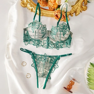 Close-up of emerald green floral embroidery lace bra and matching panty set on satin