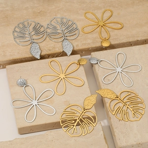 Ensemble de boucles d'oreilles fleurs et feuilles dorées et argentées sur pierre