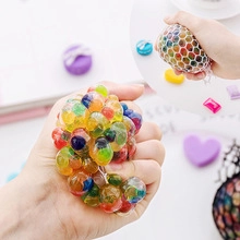 Close-up of colorful mesh squishy ball being squeezed showing grape-like texture