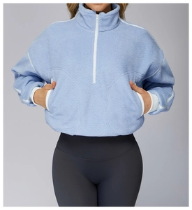 Detailed texture of light blue sherpa fleece fabric on women's cropped half-zip jacket