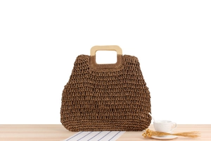 Gros plan sur un sac cabas en paille tissée avec poignées en bois et texture ajourée