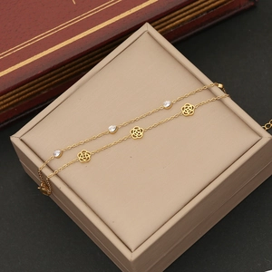 Close-up of golden chain bracelet featuring hollow flowers and teardrop zircon charms