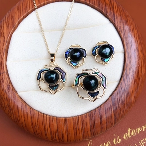Macro detail of black pearl jewelry set with camellia shell design in a gift box