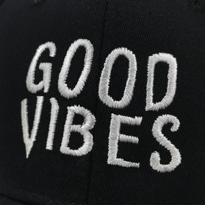 Gros plan sur la broderie 3D blanche GOOD VIBES sur une casquette en toile de coton noir