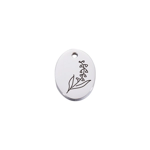 Macro detail of oval stainless steel necklace pendant with engraved botanical floral pattern