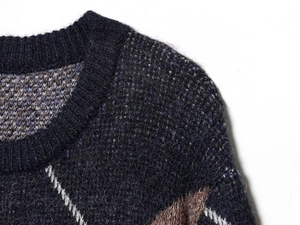 Macro view of argyle knit pattern and textured fuzzy mohair blend on ribbed crew neck