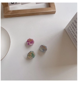 Detailed view of three shell-shaped hair clips in gradient purple blue and green tones