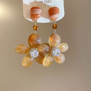 Detailed view of amber resin flower earrings with sparkling zircon centers and marble texture