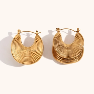 Macro shot of gold chunky hoop earrings featuring textured ripple pattern and polished finish