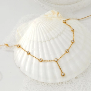 Minimalist stainless steel zircon chain necklace elegantly draped over a white shell