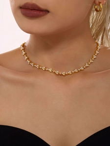 Close-up of a gold pearl flower necklace and hoop earring set worn by a female model