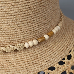 Makro-Detail von handgewebtem Raffia-Sonnenhut mit Perlen und Holz-Akzenten im Ethno-Stil