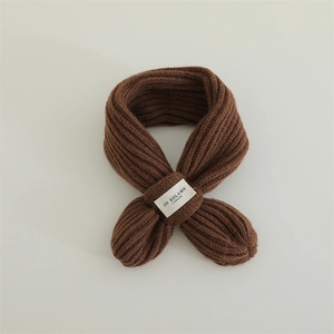 Detail shot of caramel brown chunky knit scarf with crossover design and woven label