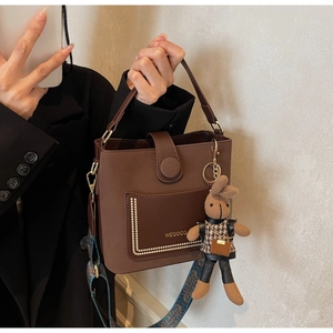 Detail of caramel brown bucket bag with gold rivets and colorful patterned wide shoulder strap
