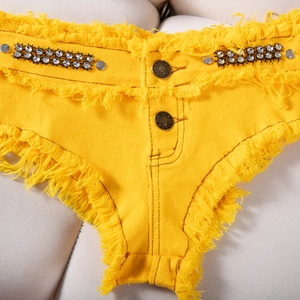 Dettaglio di pantaloncini in denim giallo vivace con passanti in strass e bordi sfilacciati