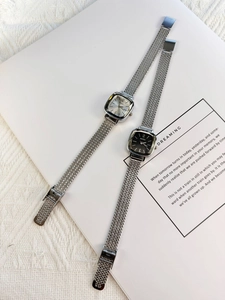 Detail of square quartz watches with black and silver dials and metal mesh bands