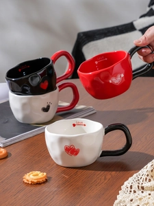 Close-up of stacked heart-shaped ceramic mugs with Love engraving and heart pattern